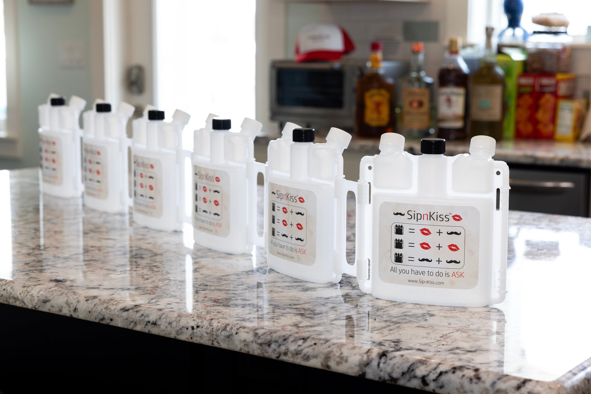 A row of white SipnKiss dual-mouth drink dispensers 